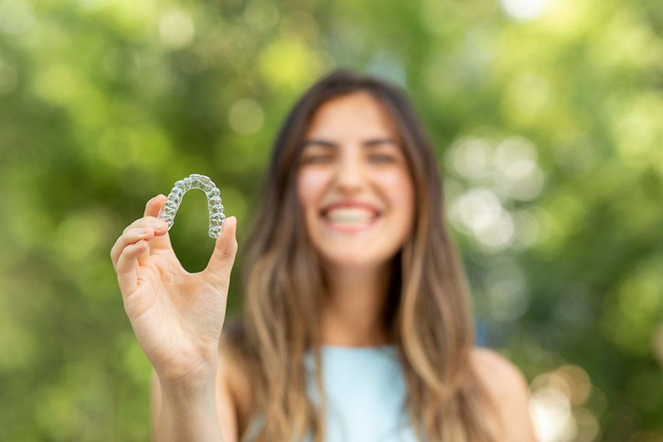 young girl holding up an Invisalign tray