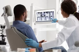 Dentist explaining dental X-rays to a patient during a consultation at Mint Dental, emphasizing oral health assessment and treatment options.
